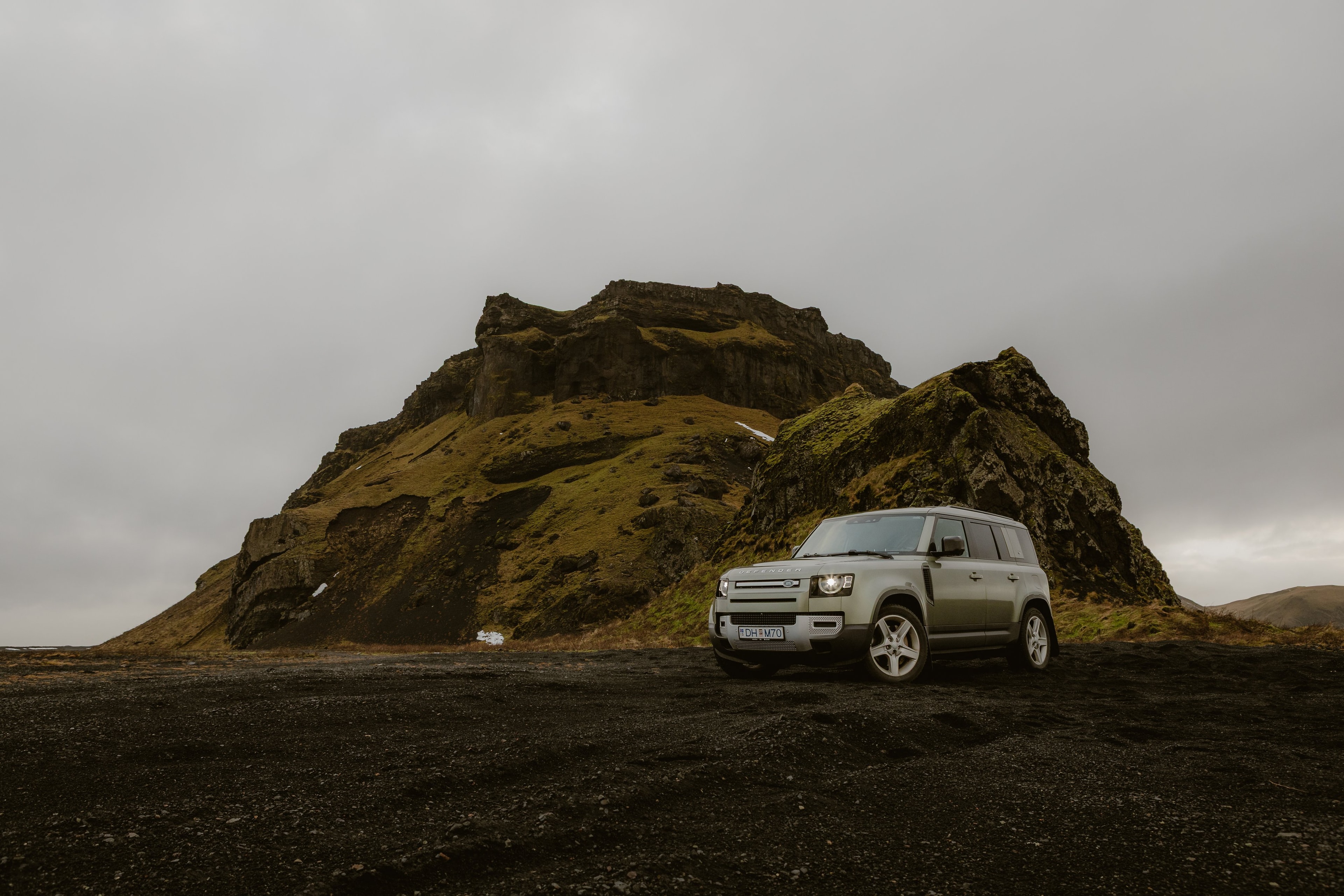 Land Rover Defender vor einem grünen Felsberg