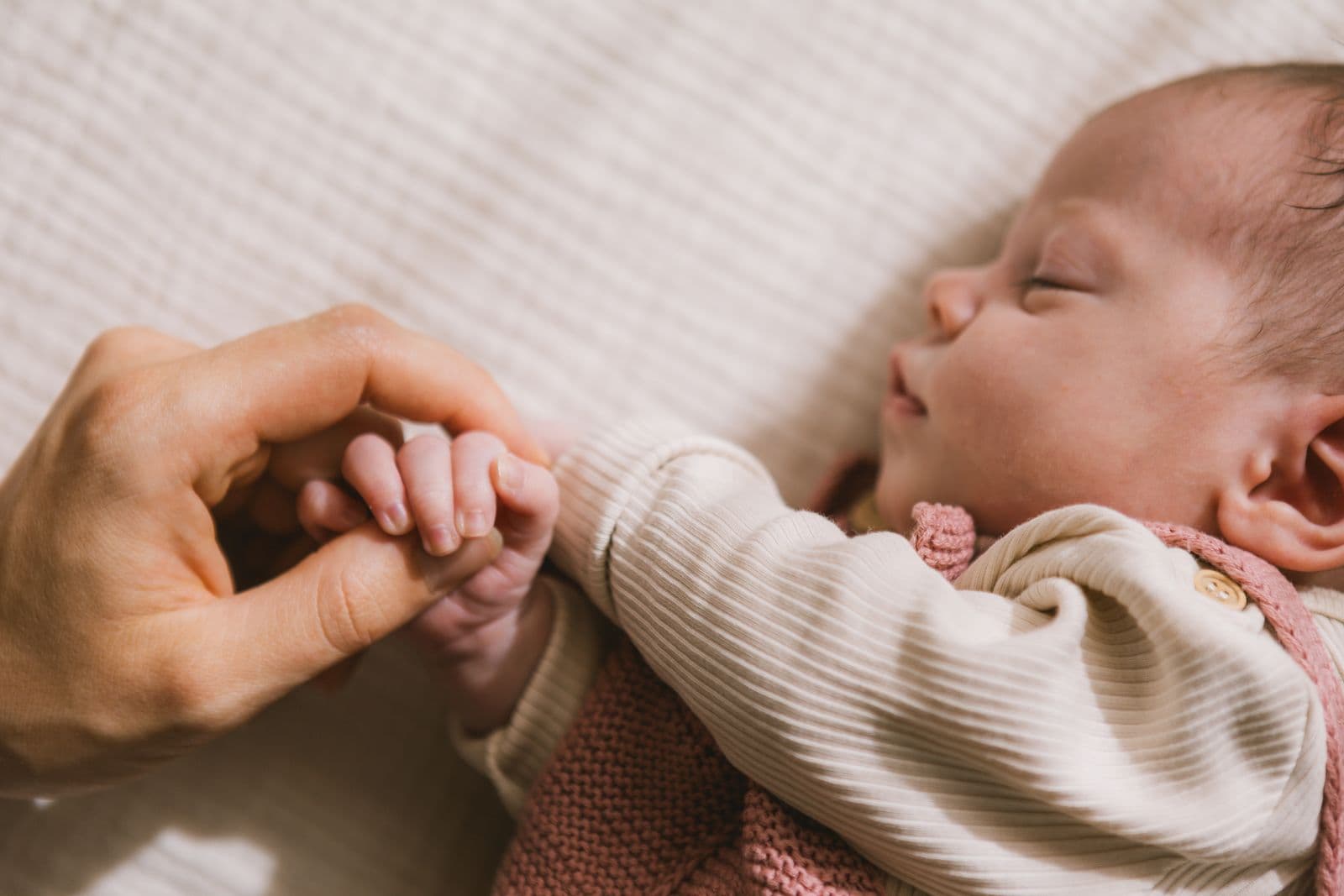 Schlafendes Baby hält Mamas Hand